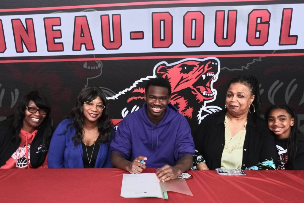 Juneau-Douglas High School: Yadaa.at Kalé senior Ahmir Parker, center, signed a letter of intent Thursday in the JDHS commons to attend Waldorf University in Forest City, Iowa, and play soccer for the Viking Warriors. From left are Parkers maternal grandmother Michelle Monts, mother Kelli Patterson, Ahmir Parker, grandmother Sherry Patterson and little sister Makaylah Patterson. (Klas Stolpe / Juneau Empire)
