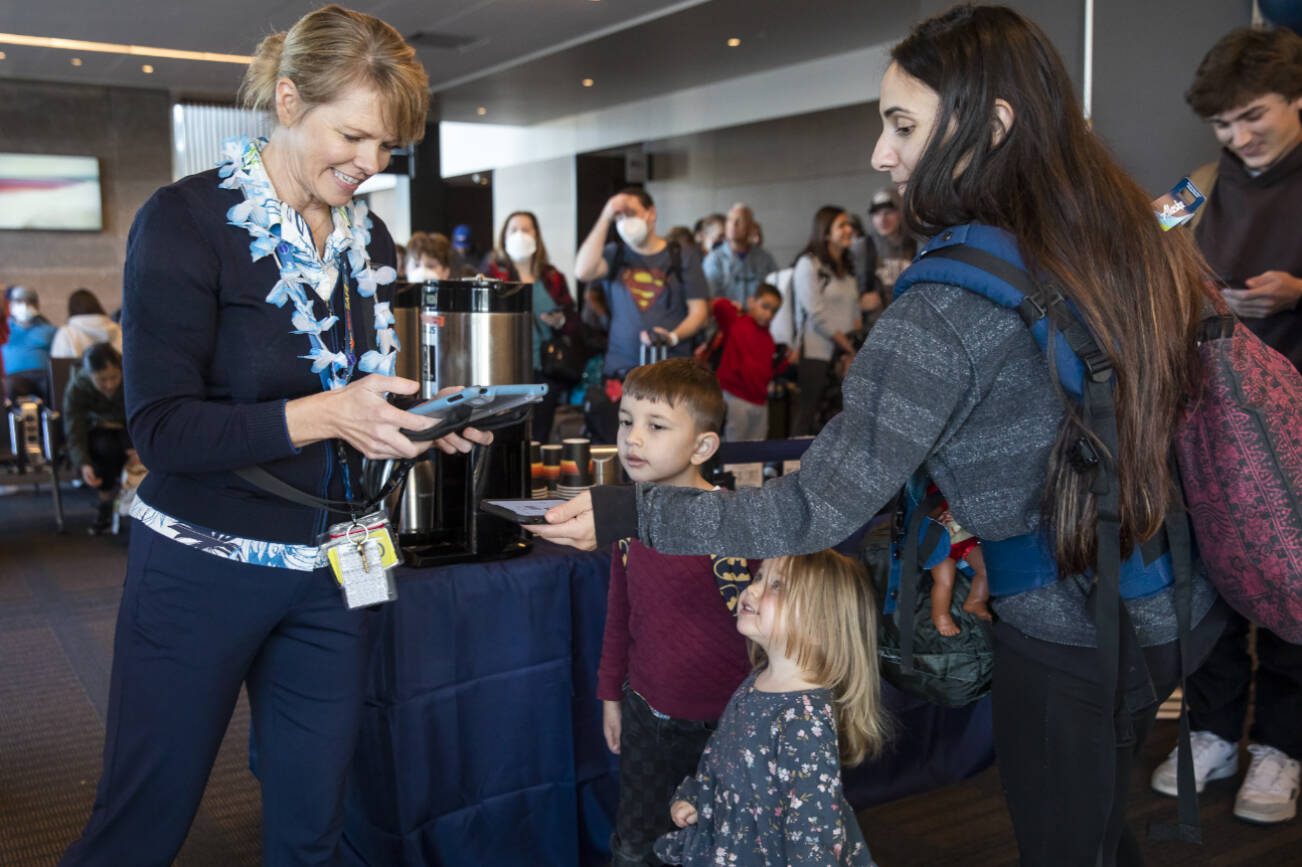 Katie Wallace, left, checks people into the first flight from Paine Field to Honolulu on Friday, Nov. 17, 2023 in Everett, Washington. (Olivia Vanni / The Herald)