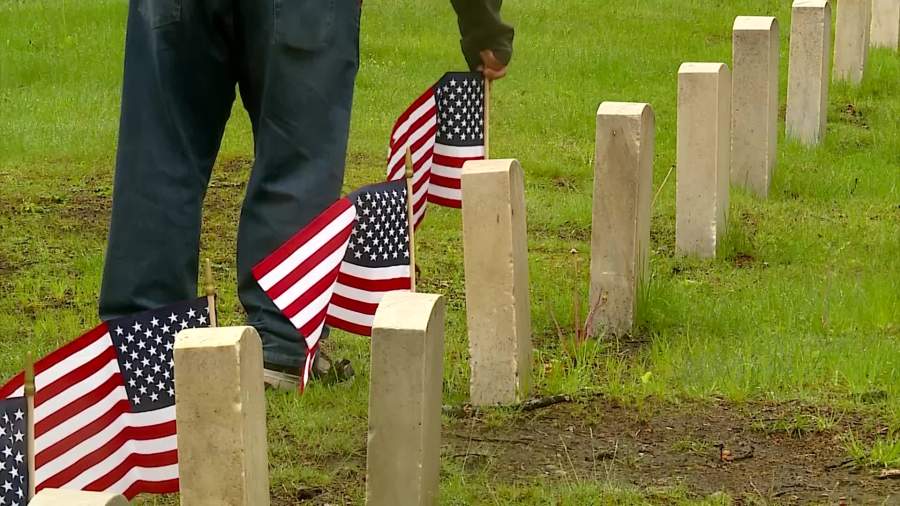 Volunteers place flags on gravesites to honor veterans