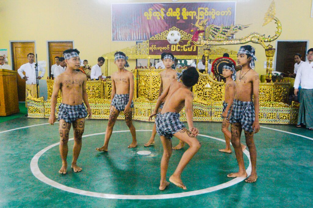 Myanmar youths are seen playing Chinlone in a traditional circular formation.