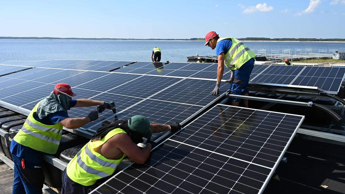 Workers constructing a floating photovoltaic solar energy farm near Cottbus, Germany. China  produces over 80% of the world’s solar panels