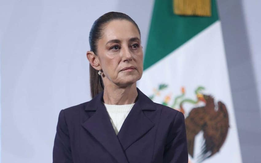 President Claudia Sheinbaum stands in front of a Mexican flag