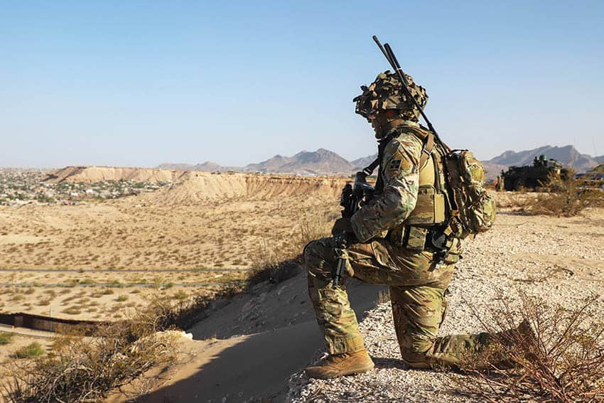 A US soldier in camo surveils a desert valley in New Mexico