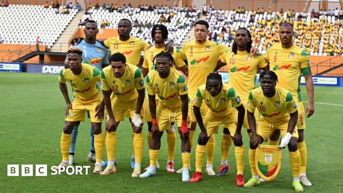 Ten Benin players, all wearing yellow shirts yellow shorts and yellow socks, and a goalkeeper wearing a sky blue shirt, pose for a team photo ahead of a football match