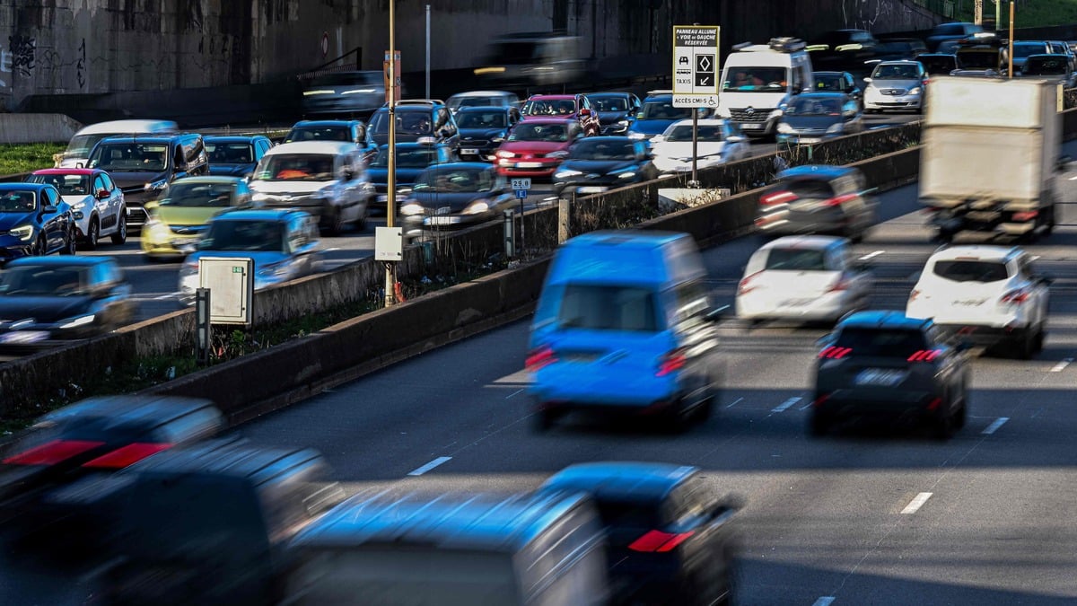 This photograph taken in Paris on March 5, 2025 shows motorists driving their cars past a road sign announcing the new carpool lane on the Paris ring road.