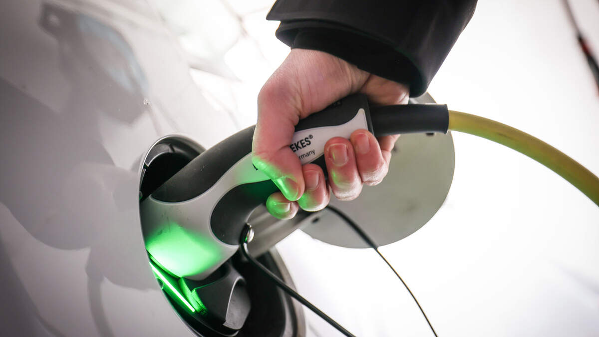 A driver puts their Electric vehicle on charge (library image)