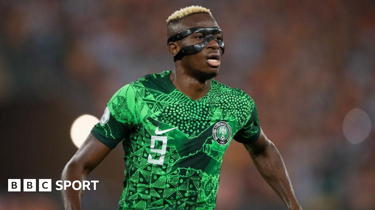 Victor Osimhen wearing the Nigerian green jersey and a black mask on his face looks sideways during a 2023 Afcon match