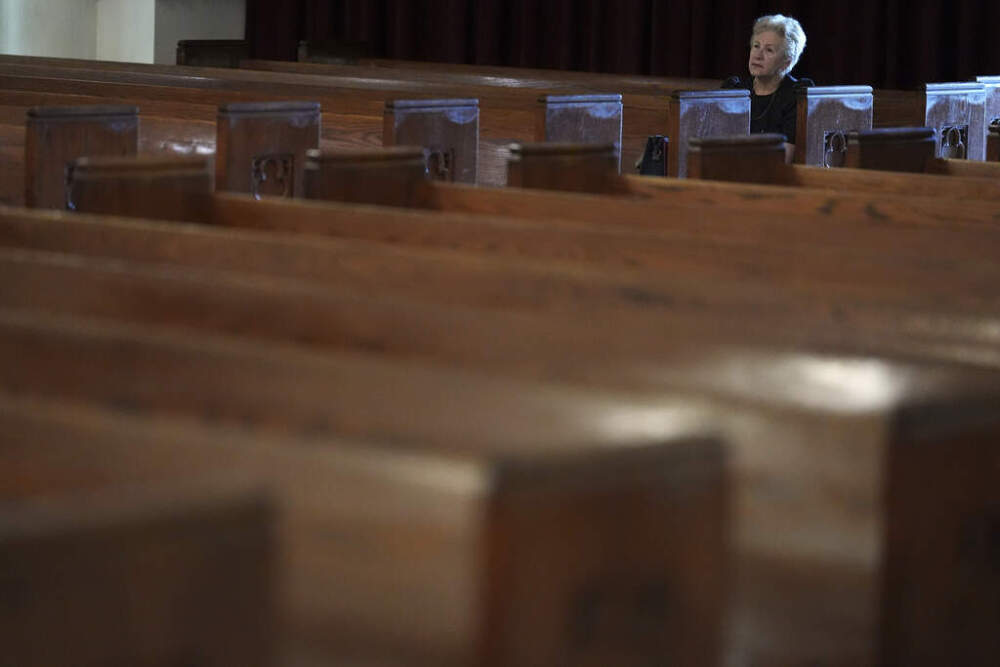 A person sits in a rear pew inside Church of the Little Flower, where a picture of Pope Francis was on display, Monday, April 21, 2025, in Coral Gables, Fla. (AP Photo/Rebecca Blackwell)