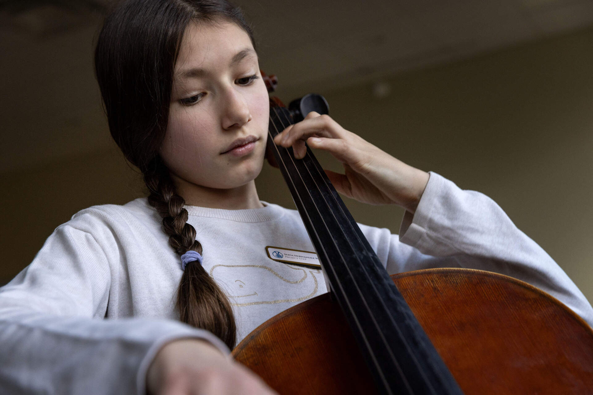 Sofia Hernandez-Williams plays cello at WBUR with her stuffy Caitriona by her side. (Robin Lubbock/WBUR)