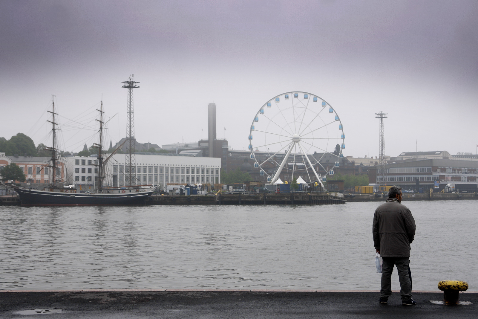 A man in grey attire looks at the sea from the edge of the Cholera Basin in the western harbour near Market Square in Helsinki. Photograph by Tony Öhberg for Finland Today.
