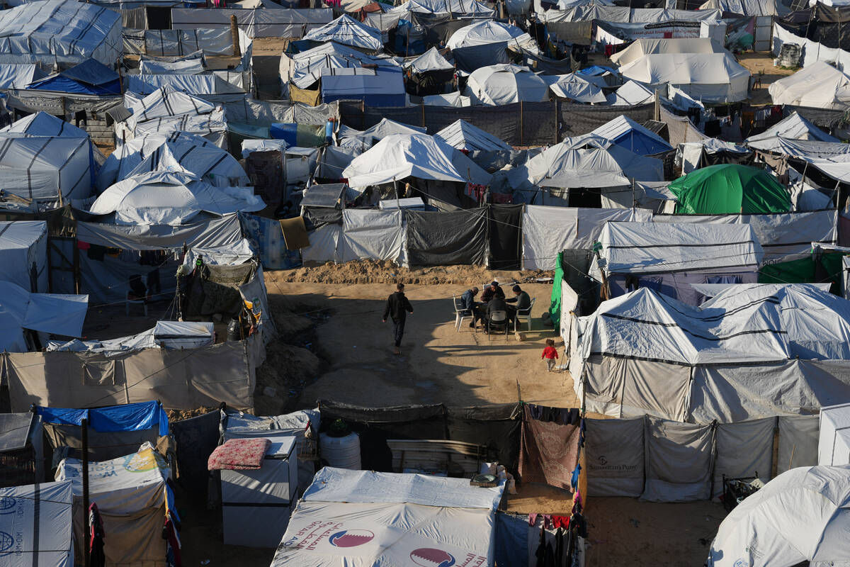 Displaced Palestinians gather outside a tent at a temporary camp in Deir al-Balah, central Gaza ...