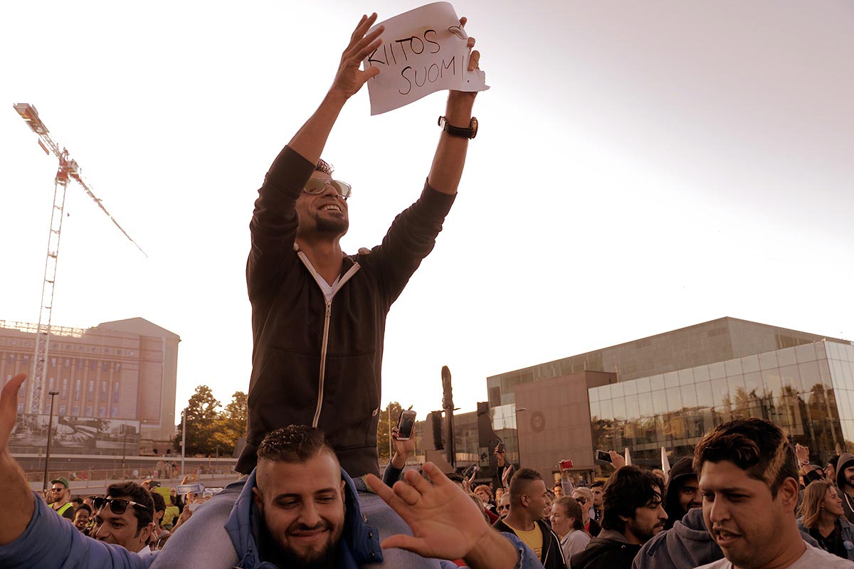A man holding a sign that reads "Thank you Finland!" at a welcoming picnic for refugees in Helsinki on September 12, 2015. Photograph by Tony Öhberg for Finland.