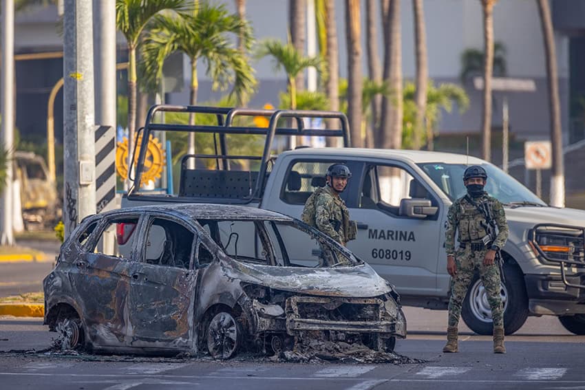 Mexican marines inspect a burned car in Puerto Vallarta