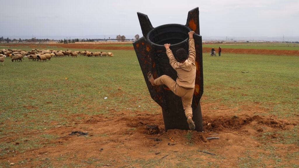 A boy attempts to climb an Iranian missile that fell in an open field on the outskirts of Qamishli (in northeastern Syria), March 4, 2026 (Badrkhan Ahmad/AP)