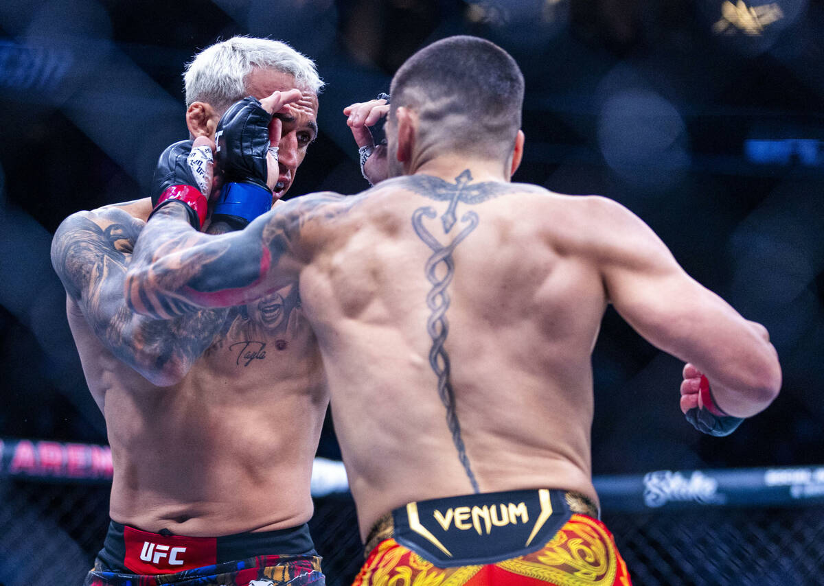 Charles Oliveira is struck on the side of the face by Ilia Topuria during their lightweight tit ...