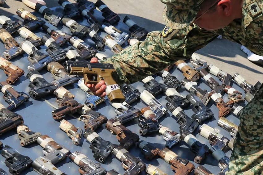 A soldier displays seized handguns