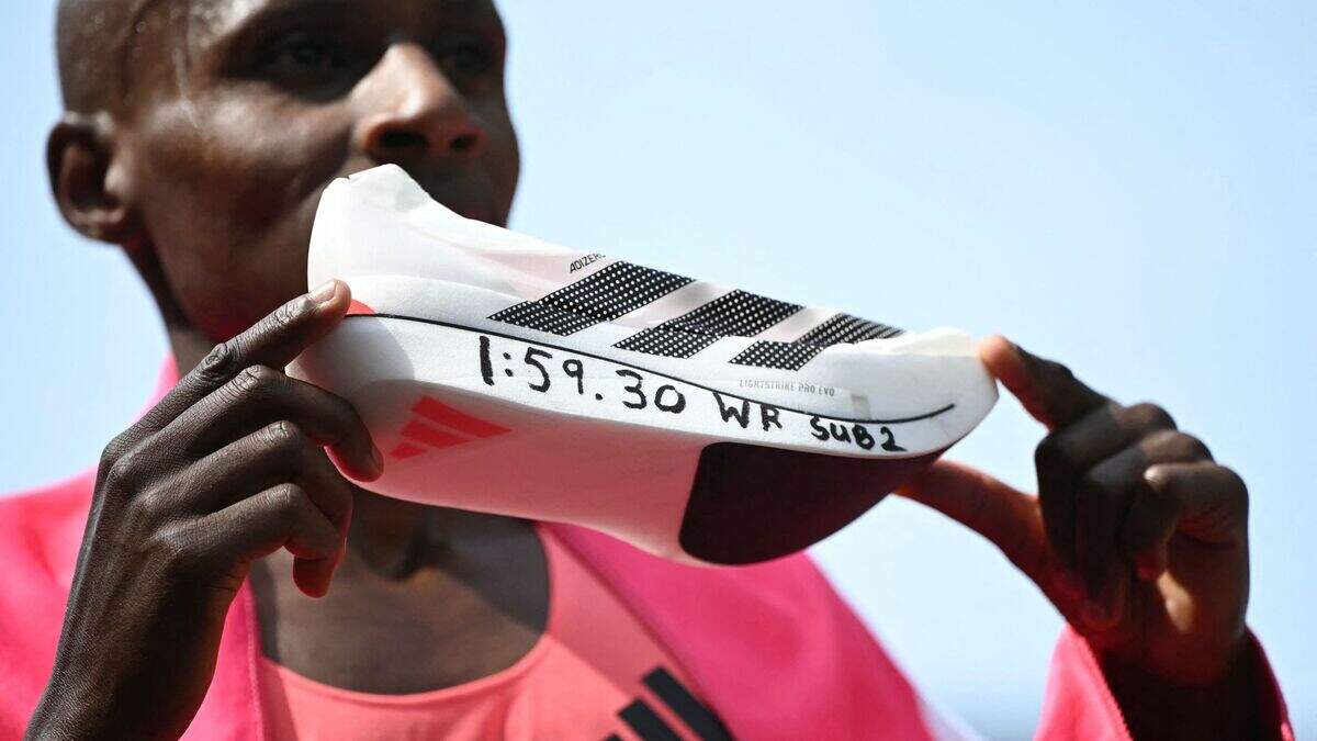 Kenya's Sabastian Sawe poses with his new world record time written on his Adidas Adizero Adios Pro Evo 3 running shoe at the finish of the 2026 London Marathon