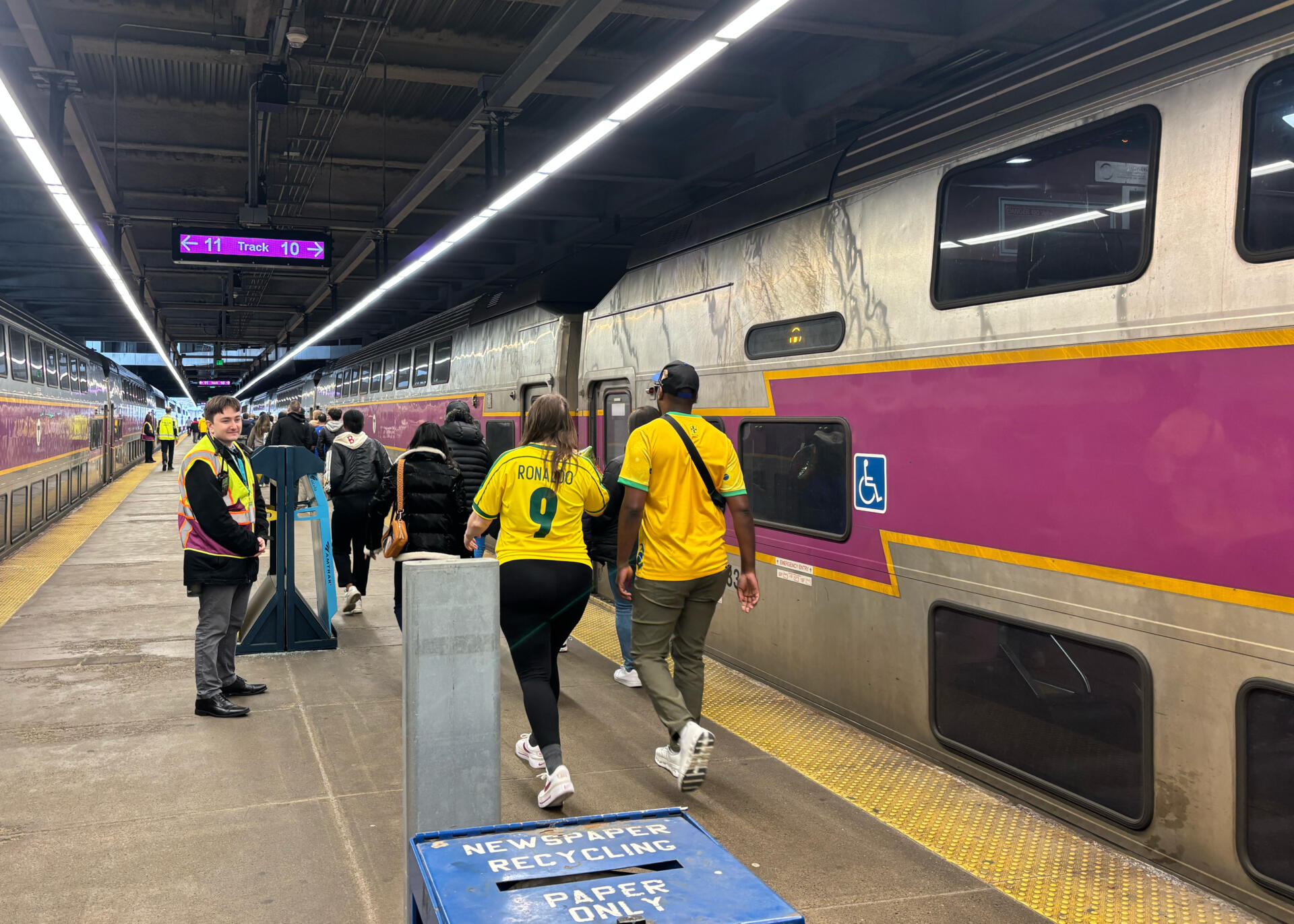 Fans in Brazil jerseys walk down the platform at South Station to board an event train headed for Gillette Stadium. (Katie Cole/WBUR)