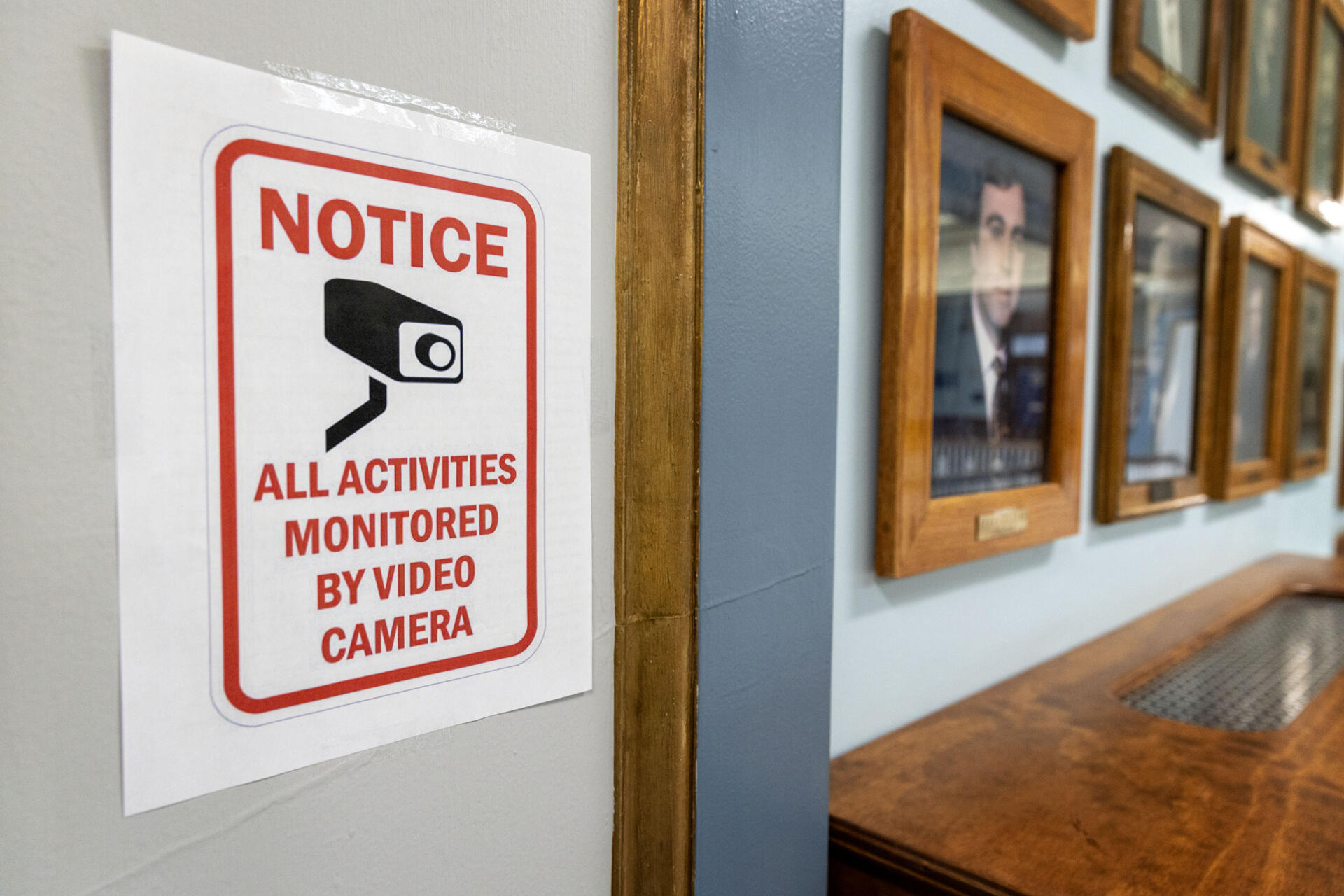 A camera attached to the ceiling, and a sign warning visitors about live video cameras, seen near the mayor's third floor office at Lawrence City Hall. (Robin Lubbock/WBUR)