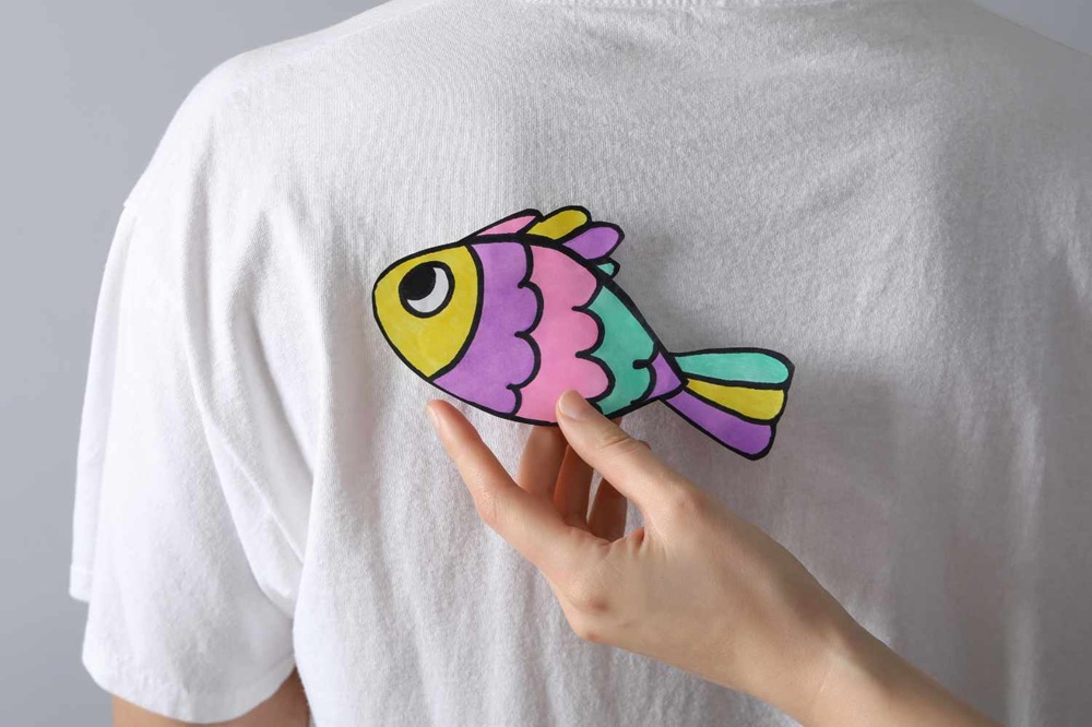 What's behind the tradition of the pesce d'aprile? Image shows someone sticking a colourful paper fish to the back of another.
