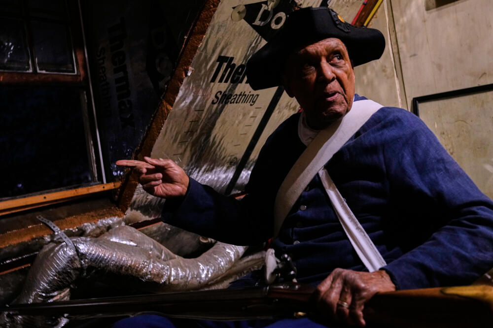 Colonial minute man Charlie Price, 95, takes a perch in a window of the Buckman Tavern prior to a historic re-enactment of the Battle of Lexington, Saturday, April 18, 2026, in Lexington, Mass. (AP Photo/Charles Krupa)