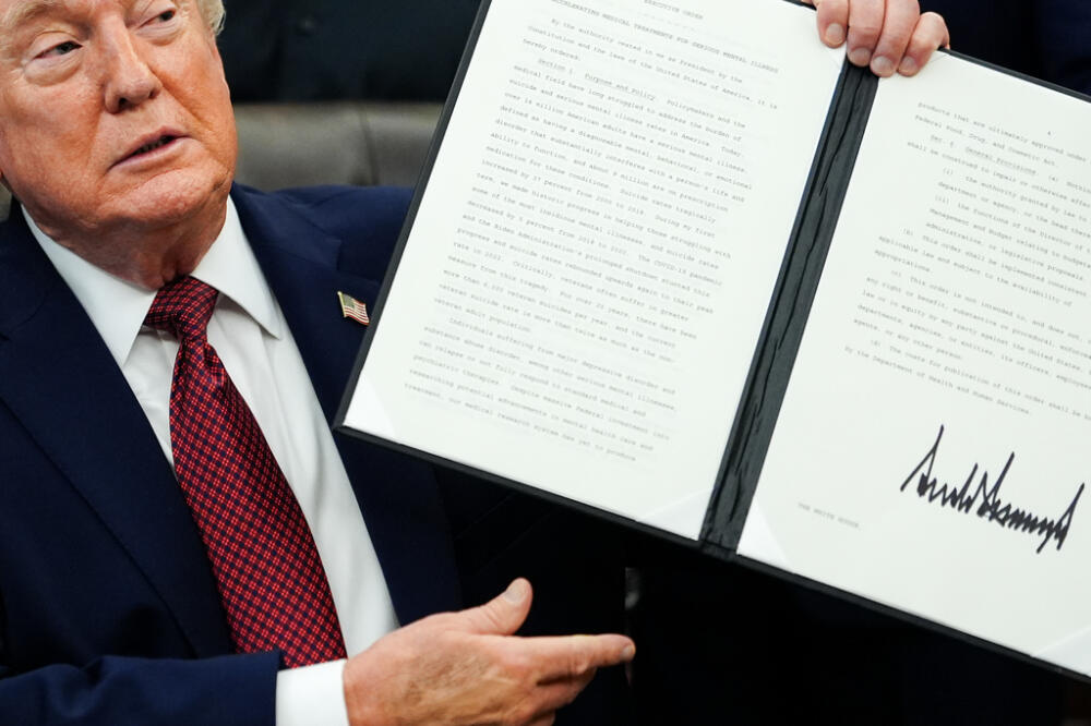 President Donald Trump holds up a signed executive order in the Oval Office of the White House, Saturday, April 18, 2026, in Washington. (AP Photo/Julia Demaree Nikhinson)