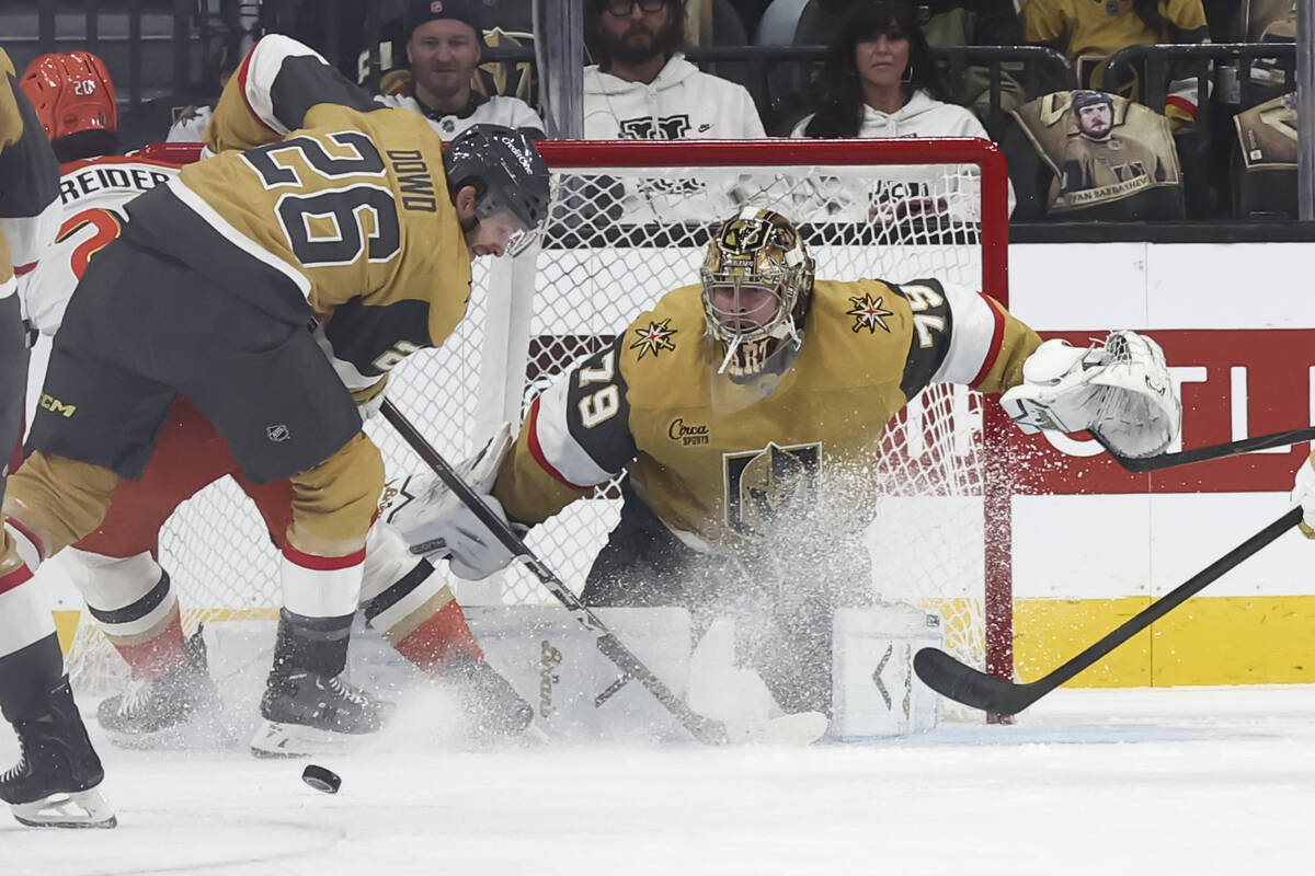 Golden Knights goaltender Carter Hart (79) watches the puck rebound as center Nic Dowd (26) def ...