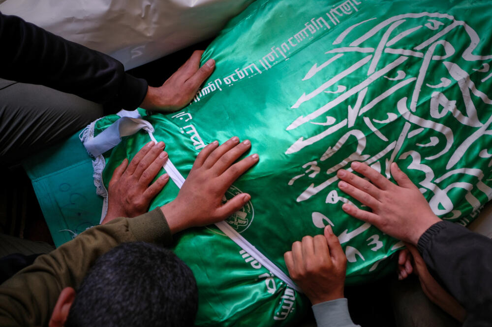 Palestinians place their hands on the body of Izz al-Din al-Haddad, the leader of Hamas' Qassam Brigades, draped in a Hamas flag during his funeral in Gaza City, Saturday, May 16, 2026. (AP Photo/Jehad Alshrafi)