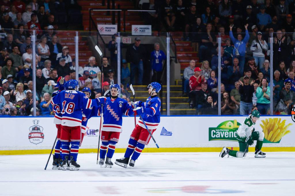 The Kitchener Rangers celebrate a goal as Silvertips defenseman Kayd Ruedig rises back to his feet during Kitchener’s 6-2 win against Everett in the Memorial Cup round-robin at Prospera Place on May 25, 2026. (Photo courtesy Steve Dunsmoor / CHL)