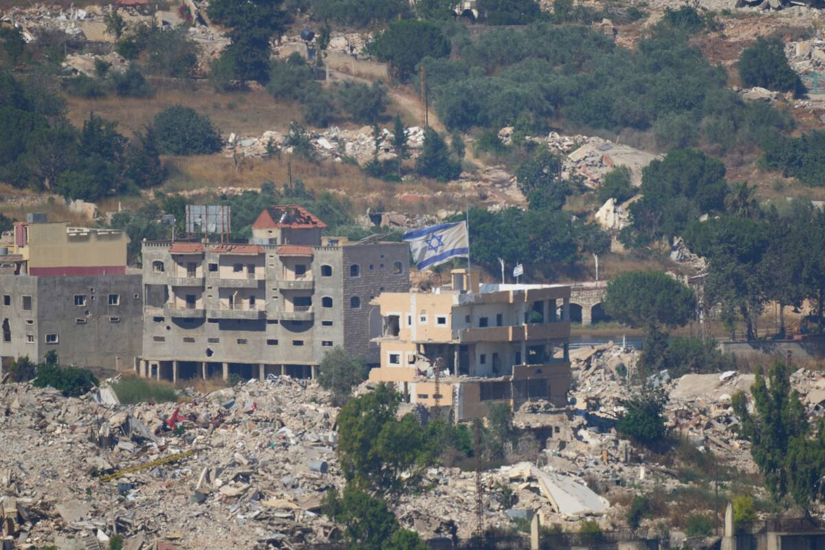 An Israeli flag tops a destroyed building in southern Lebanon, as seen from northern Israel, Su ...