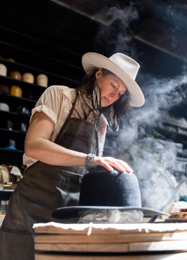 Jac Cash shapes a hat in the workshop at FauxyFurr Vintage + Handmade on Tuesday, June 2, 2026 in Arlington, Washington. (Olivia Vanni / The Herald)