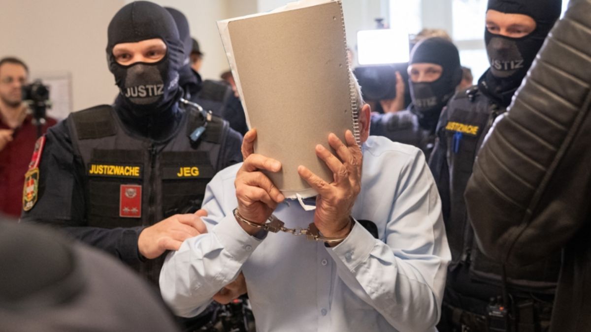 A former Syrian officer defendant covers his face while being escorted to the regional court in Vienna, Austria, June 1, 2026. (AFP)