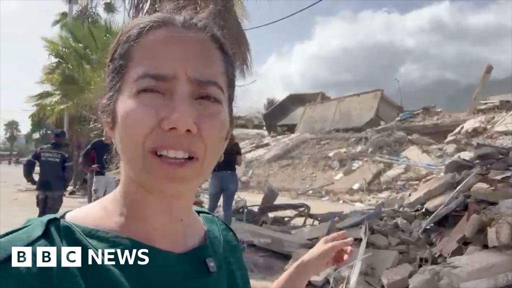 Vanessa Silva reporting from Venezuela showing destroyed buildings behind her