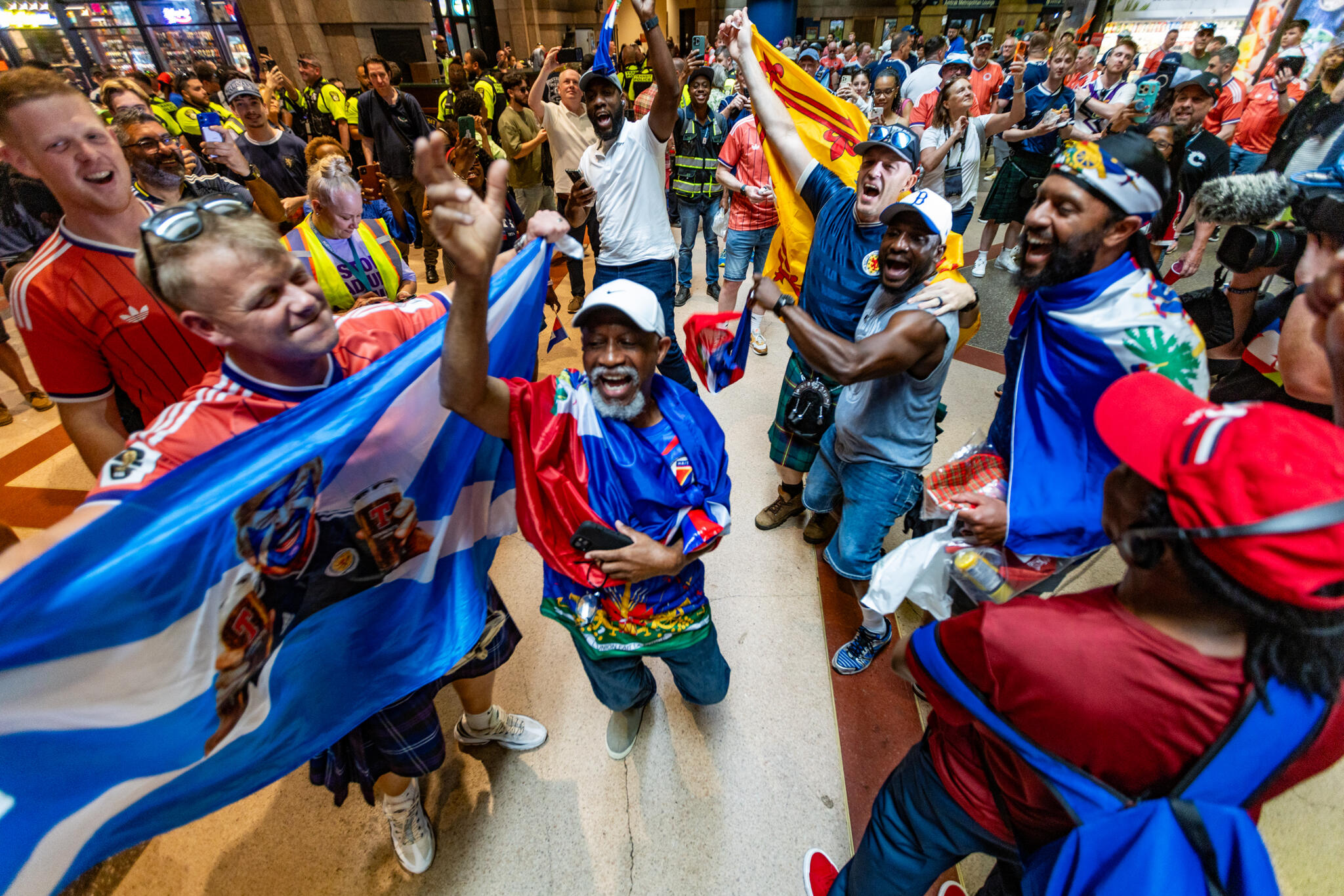 Scottish and Haitian fans dance and chant together inside South Station waiting to board MBTA trains to the World Cup match in Foxborough. (Jesse Costa/WBUR)