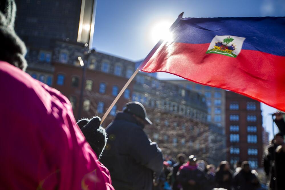 In this file photo, protesters wave a Haitian flag at Boston City Hall Plaza in 2018 after President Trump announced he wanted to end the Temporary Protected Status program for Haitians. (Jesse Costa/WBUR file)