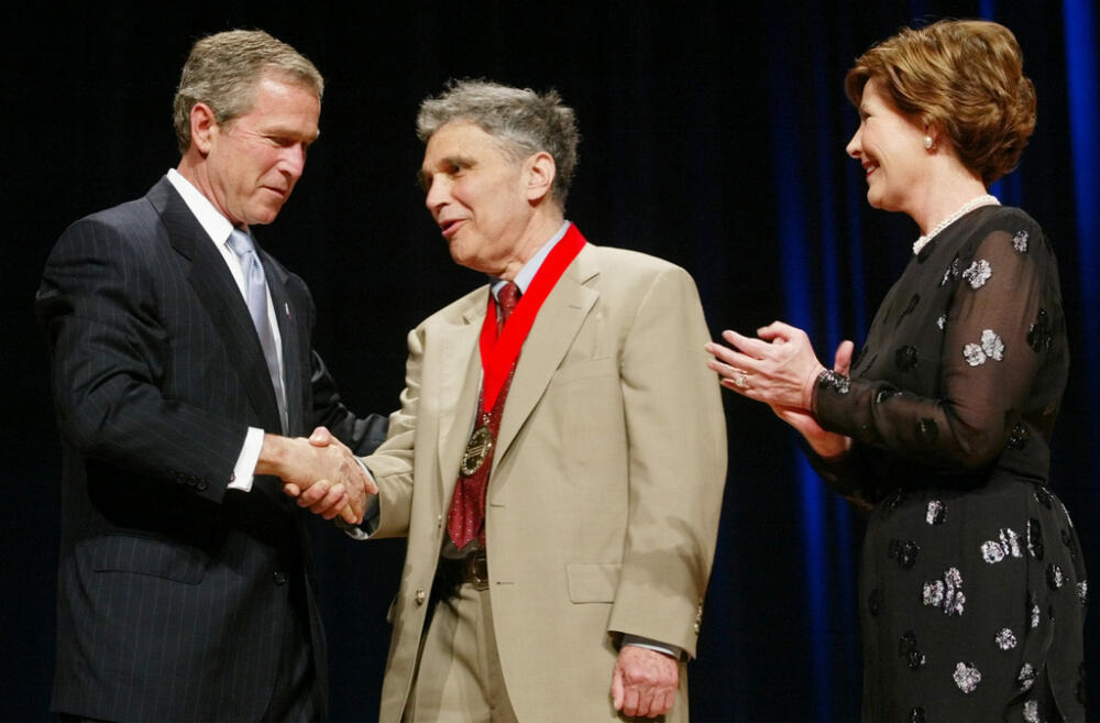 Then-President Bush, left, shakes hands with Robert Coles, center, during the National Endowment for the Arts Awards ceremony at Constitution Hall, April 22, 2002, in Washington. (Pablo Martinez Monsivais/AP, File)