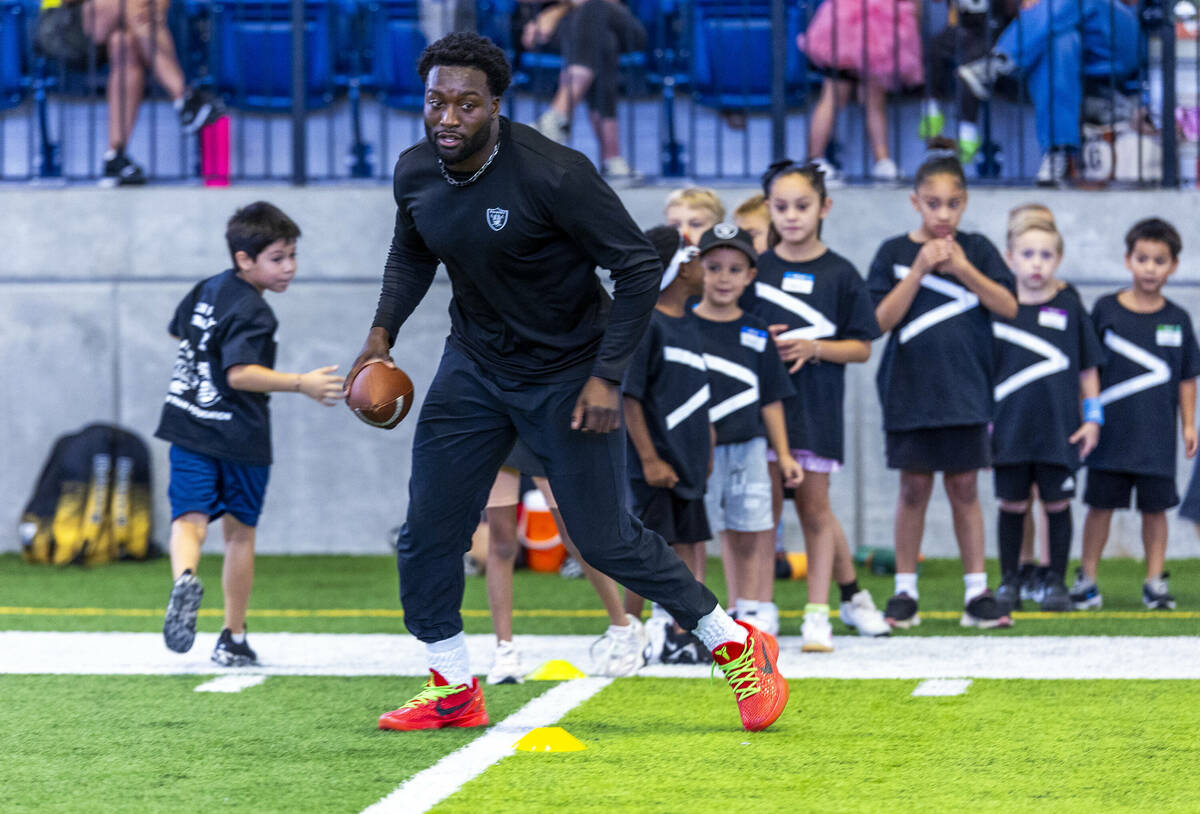 Raiders special teams player Segun Olubi demonstrates a pattern to young participants in a dril ...