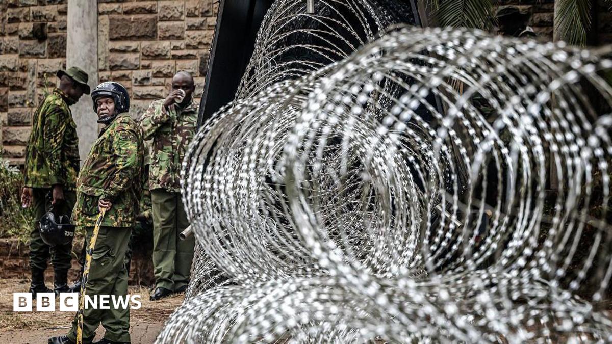 Coils of razor wire are stacked outside a government building as armed security officers stand guard