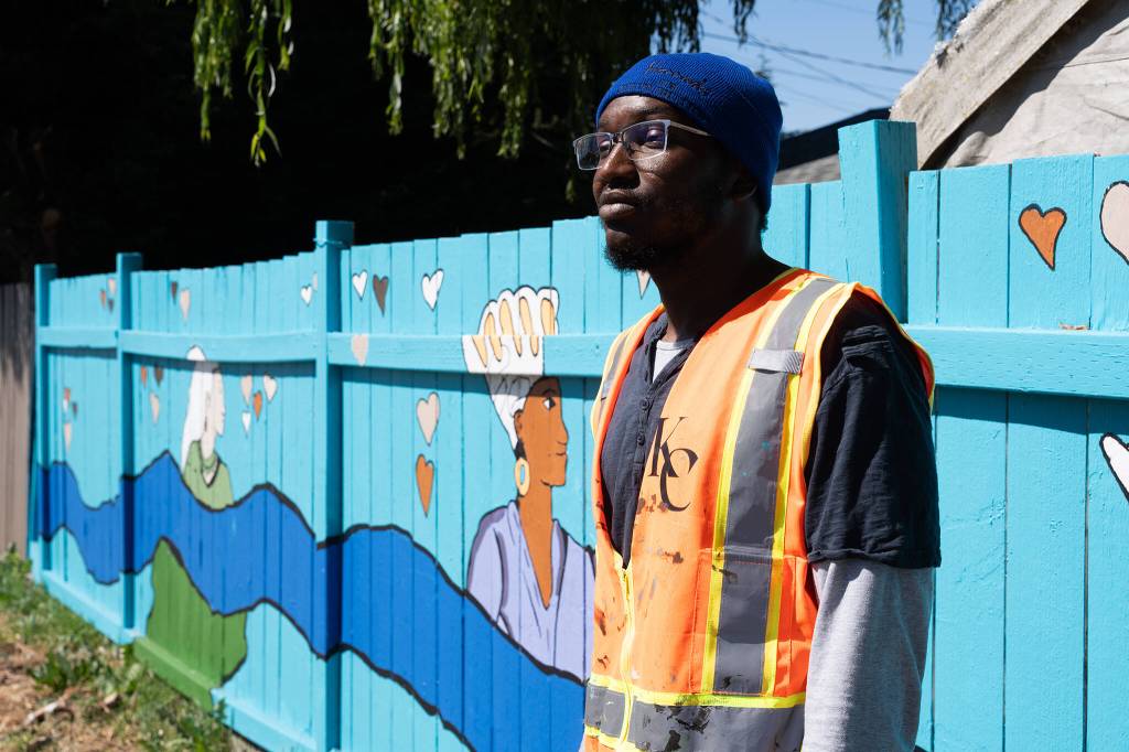 Mohamed Kujabi, the Everett artist who designed and painted murals near Voyager Middle School with help from students at the school, stands near a mural on Monday, June 22, 2026, south of Everett, Washington. (Will Geschke / The Herald)
