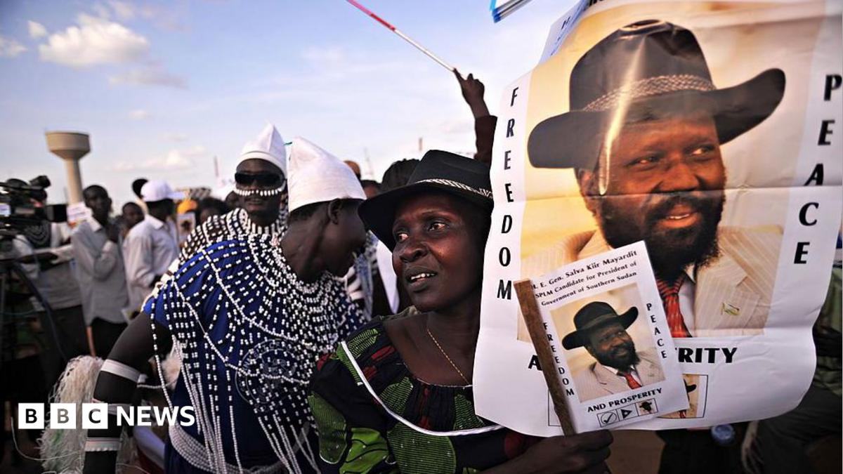 A supporter of President Salva Kiir holds up portraits of Kiir with the slogan "Freedom, Peace" during a political rally in Juba