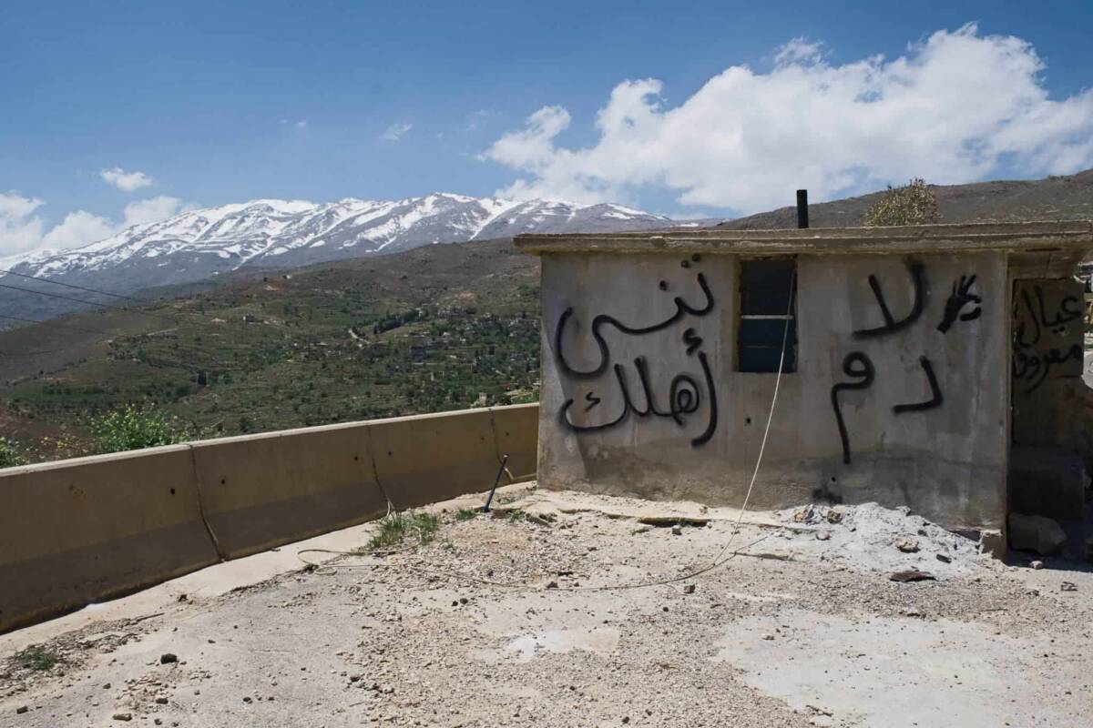 Mount Hermon, on the Syrian-Lebanese border, overlooks an unmanned checkpoint at the entrance of the Reef Dimashq village of Beqaasem. Graffiti painted on the small building reads: “Don’t forget the blood of your people,” 7/5/2026 (Hicham El Bouhmidi/Collectif DR/Syria Direct)