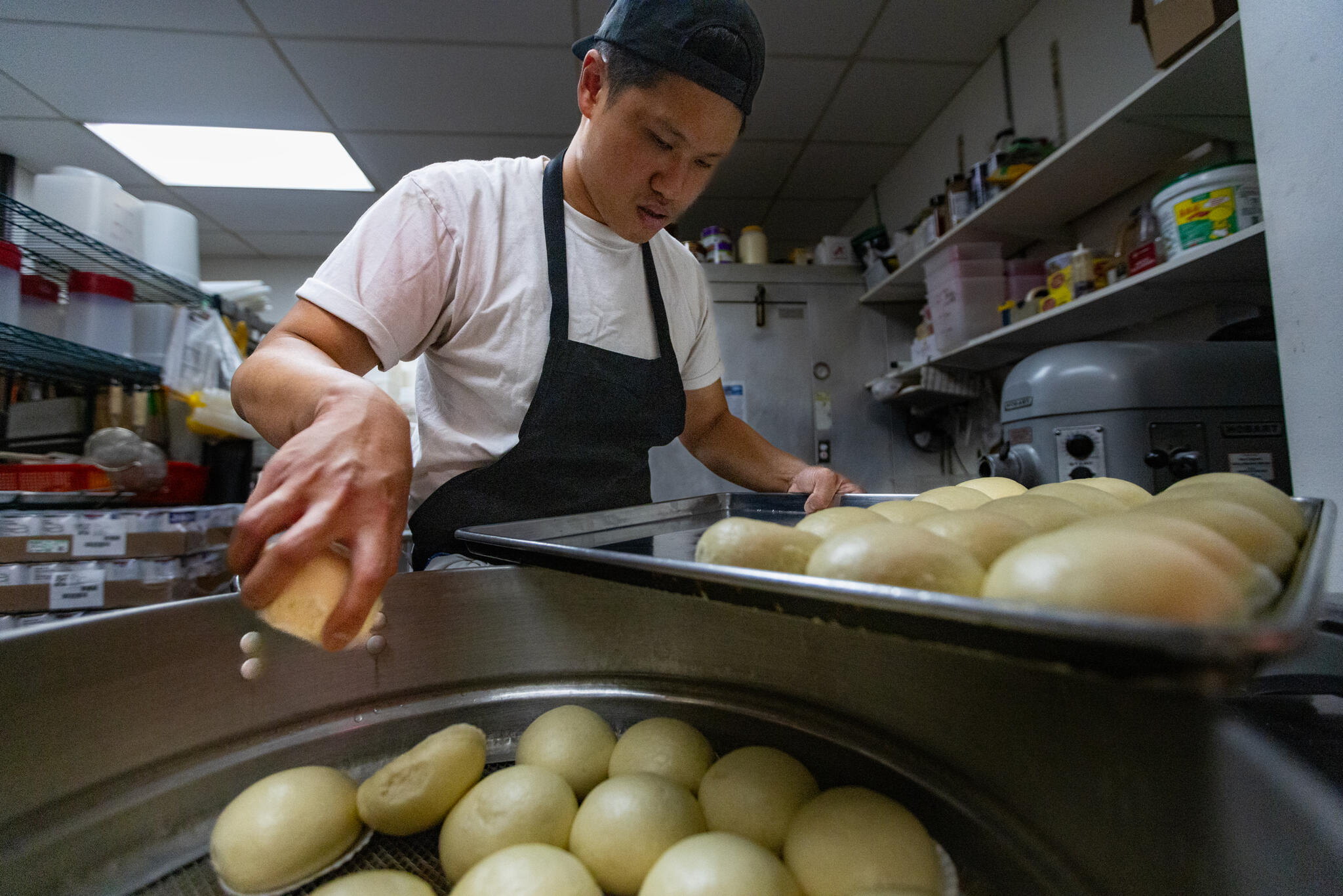 Chef Laurence Louie removes lava egg yolk bao from a steamer and places them on a tray to reheat for service at Rubato in Quincy. (Jesse Costa/WBUR)