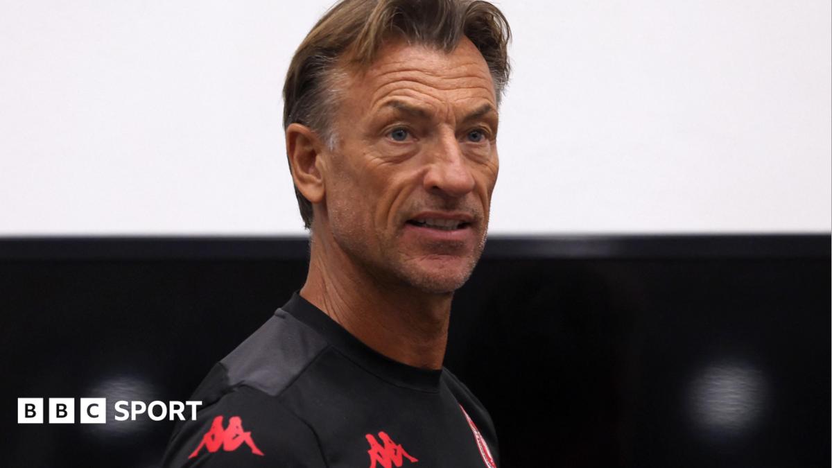 Herve Renard, visible from shoulders up, wears a wearing a black Tunisia training top as he looks over his right shoulder towards the camera