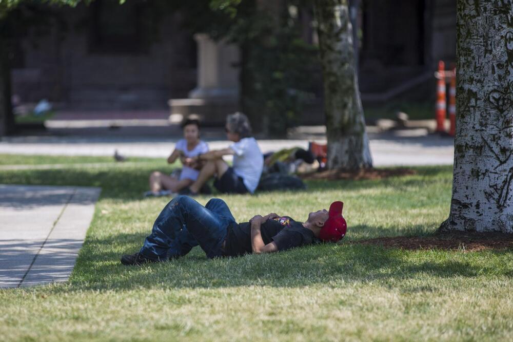 A man lays down in the shade to keep out of the hot sun in Boston in 2018. (Jesse Costa/WBUR, File)