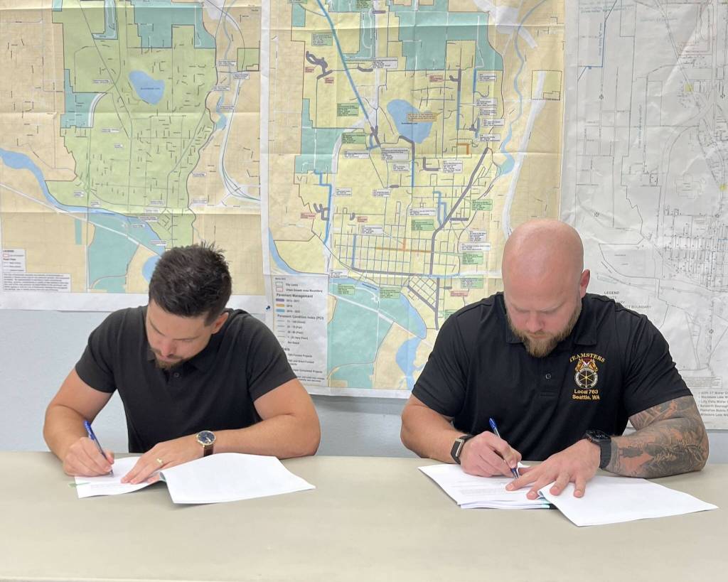 Snohomish Mayor Aaron Hoffman, left, and Teamsters Local 763 Secretary-Treasurer Chad Baker sign new collective bargaining agreements. (Provided photo)
