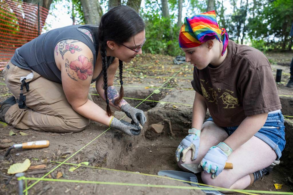 Freyr Buck reacts to a piece of pottery in the hands of Hannah Greengrass found while digging in their roped off section of the dig site at Japanese Gulch on Tuesday, July 28, 2026 in Mukilteo, Washington. (Olivia Vanni / The Herald)