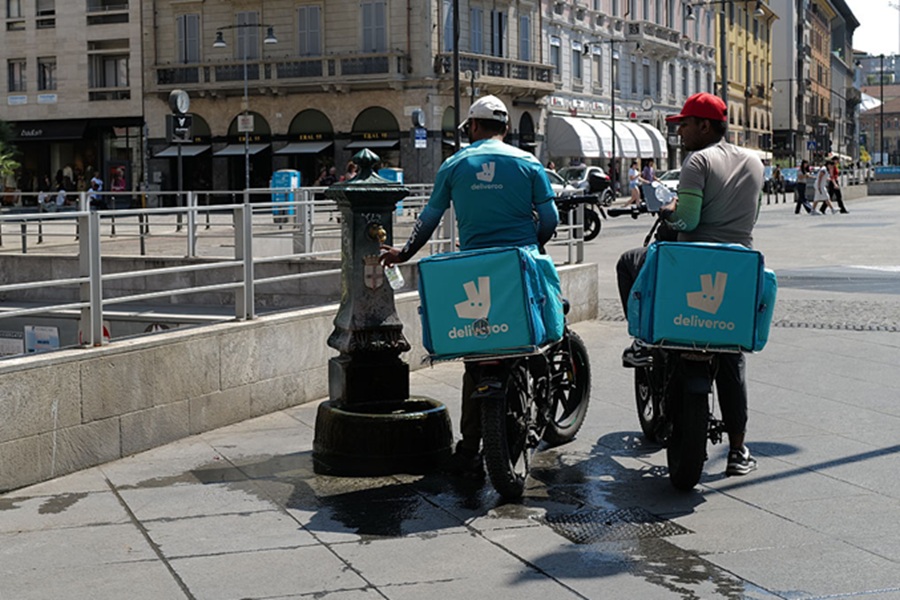 Glovo and Deliveroo investigated by Antitrust Authority. Image shows two Deliveroo riders refilling water bottles in Italy.
