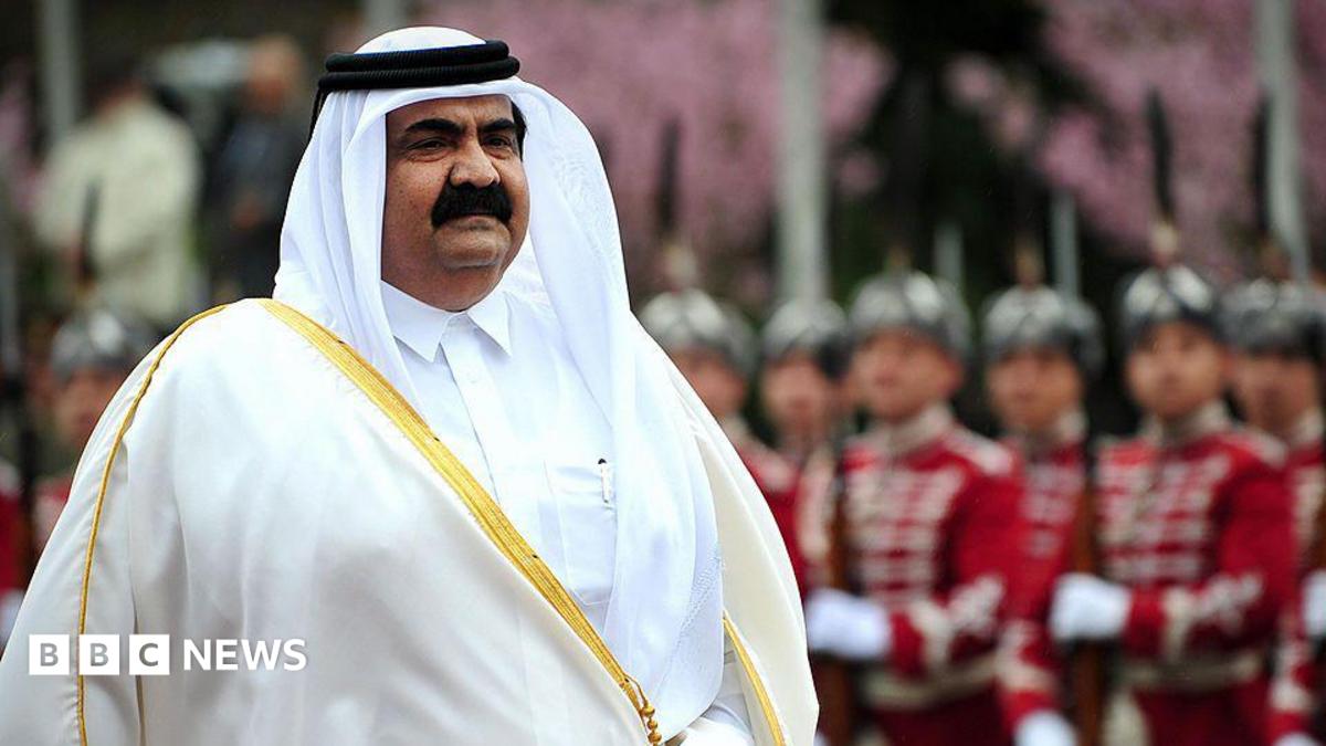 Hamad is seen wearing a white robe as uniformed military guards stand to attention behind him.