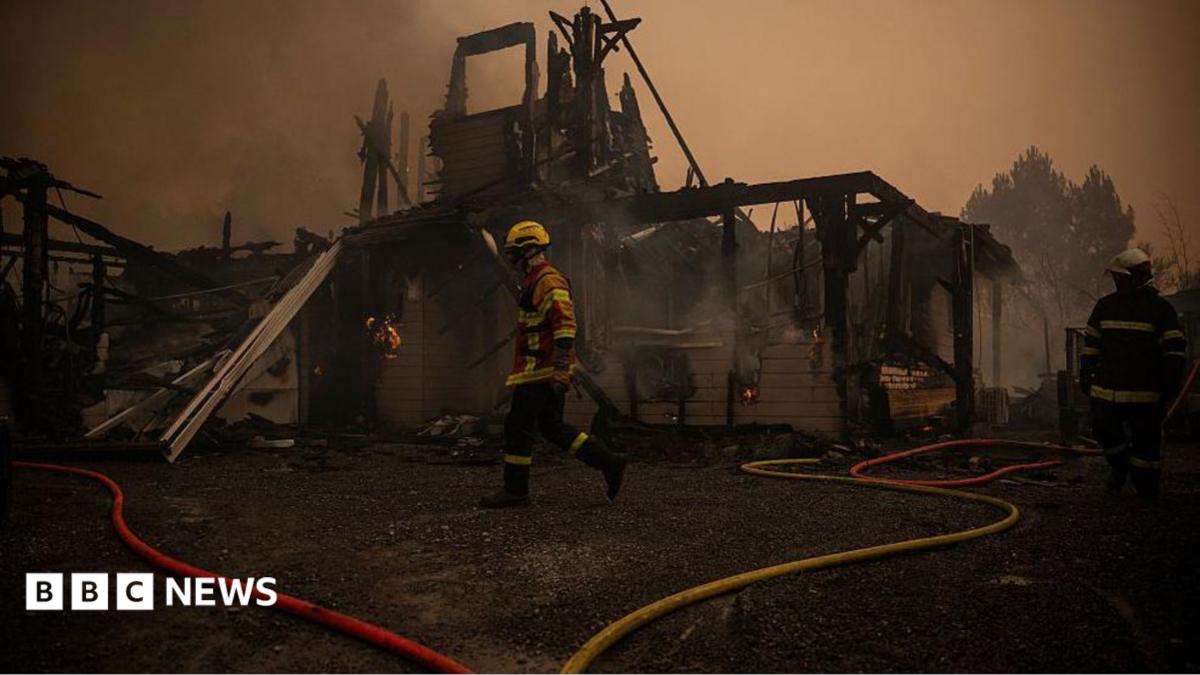 A firefighter walks in front of a burnt out building