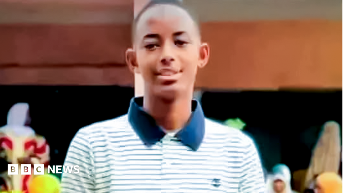 Mamadou Djouma Bah smiling, wearing a striped white and blue T-shirt